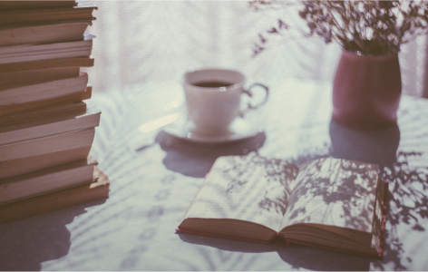 Mesa con libros, una taza de cafe y una planta